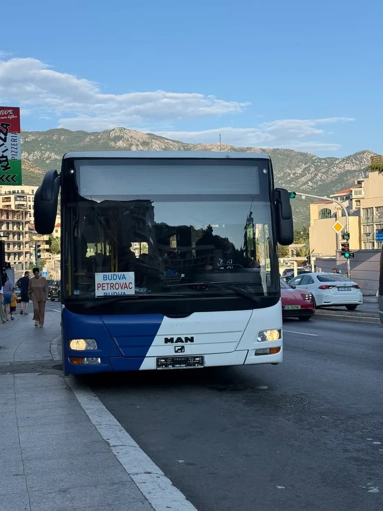 Duży autobus Mediteran Express w Budvie z białą tabliczką kierunkową BUDVA–PETROVAC za przednią szybą.